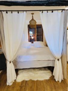 - une chambre avec un lit doté de rideaux blancs et d'un tapis dans l'établissement Location merveille de loft vue mer Bonifacio, à Bonifacio