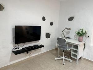 Dieses weiße Zimmer verfügt über einen Schreibtisch, einen TV und einen Stuhl. in der Unterkunft Casa (bajo), Tasarte. in Playa de Tasarte