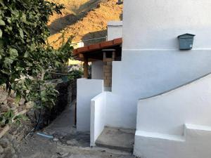 een wit gebouw met een trap naast een heuvel bij Casa (bajo), Tasarte. in Playa de Tasarte