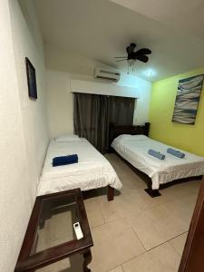 a bedroom with two beds and a table and a fan at Casa Mar in Manuel Antonio