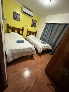 two beds in a room with yellow walls at Casa Mar in Manuel Antonio