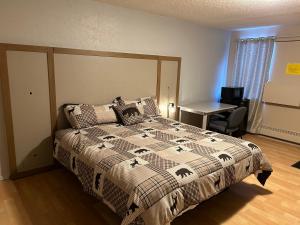 a bedroom with a bed with a comforter and a desk at Kings Court Motel in Cold Lake