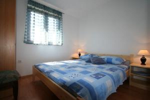 a bedroom with a bed with a blue comforter and a window at Apartment Ruzmarin in Šilo