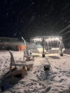 um parque infantil coberto de neve à noite com neve a cair em Cabana Duda em Subcetate