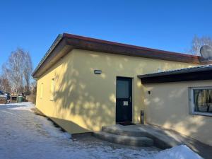 un edificio amarillo con una puerta y escaleras en la nieve en Ferienwohnung Kornkäfer 3, en Döbeln