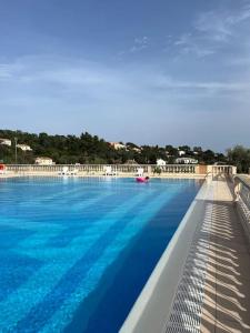 a large swimming pool with blue water at Appartement en résidence vue sur mer in Roquebrune-sur-Argens