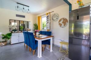eine Küche mit einem Tisch, blauen Stühlen und einem Kühlschrank in der Unterkunft Le calme du Vauclin in Le Vauclin