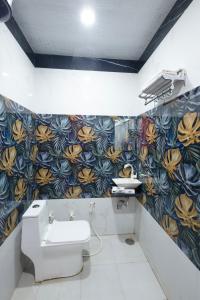 a bathroom with a toilet and a flower patterned wall at Hotel Superhouse by Wisdom Madhav in Mathura