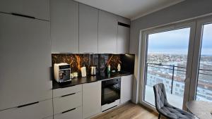 una cucina con armadi bianchi e una grande finestra di Apartament Bułgarska 59 - sypialnia i salon - 40m2 - self check in 24h a Poznań