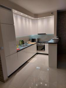 eine Küche mit weißen Schränken und einem Waschbecken in der Unterkunft Apartament in Legionowo