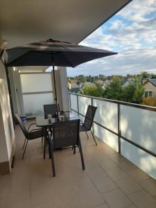 balcone con tavolo, sedie e ombrellone di Apartament a Legionowo