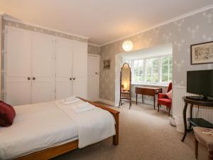 een slaapkamer met een bed, een bureau en een televisie bij Beckhythe Cottage in Cromer