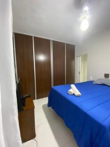 sypialnia z niebieskim łóżkiem i telewizorem w obiekcie Apartamento à 3 minutinhos da praia do forte w mieście Cabo Frio