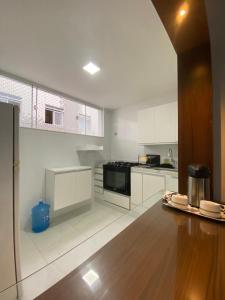 a kitchen with white cabinets and a wooden floor at Apartamento à 3 minutinhos da praia do forte in Cabo Frio