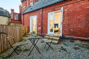 a patio with a table and chairs next to a brick building at Perfect for Professionals in LS1 & LGI - Private Garden! Contact us for Better Offers! in Leeds