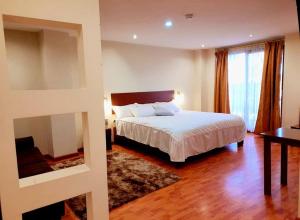 - une chambre avec un lit blanc, un bureau et une fenêtre dans l'établissement San Rafael Hotel, à Guaranda