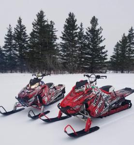 Dos motos de nieve están estacionadas en la nieve en Luxury 3-Bedroom home, en Caribou