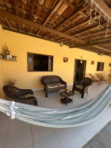 a hammock on a patio with chairs and a tv at Lar da paz - Ilha da Crôa in Barra de Santo Antônio