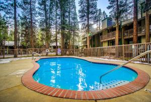 a swimming pool in front of a building with trees at Sunshine Sanctuary in Mammoth Lakes