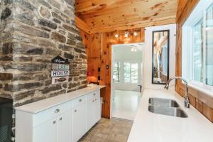 a kitchen with white cabinets and a stone wall at The Lakehouse in Carnarvon +38 photos