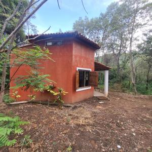 uma pequena casa vermelha no meio de uma floresta em Vila das Acácias em Vale do Capao