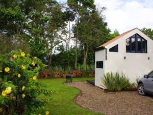 un pequeño cobertizo blanco en un patio con un coche en Luxury Glamping - Tiny House al natural en La Vega
