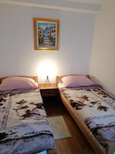 a bedroom with two beds and a lamp on the wall at Bevanda in Široki Brijeg