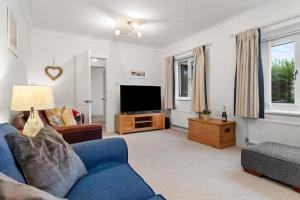 a living room with a blue couch and a tv at Kittiwake - Short Walk to Beach and Village in Saundersfoot