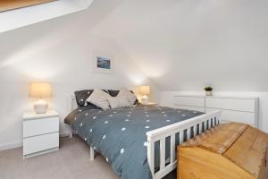 a white bedroom with a bed and a bench at Kittiwake - Short Walk to Beach and Village in Saundersfoot