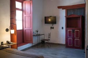 a bedroom with red doors and a desk and a television at Hotel Boutique Posada La Basilica in Pátzcuaro +45 photos
