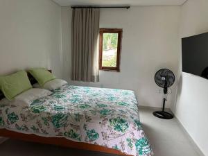 1 dormitorio con 1 cama, ventilador y ventana en Sítio aconchegante em Mulungu, en Mulungu