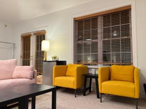 een woonkamer met 2 gele stoelen en een tafel bij Cozy 1B1B Suite 