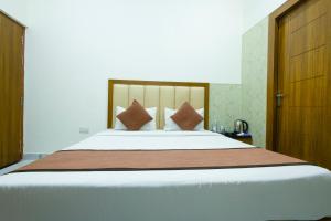 a bedroom with a large white bed with brown pillows at Hotel Lime Tree by Madhav in Mathura