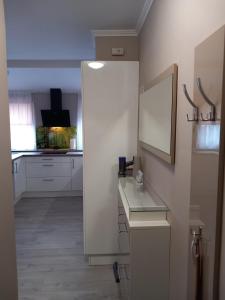 a kitchen with white cabinets and a white mirror at Prime Apartment Heviz in Hévíz