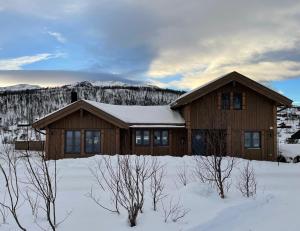 ein Holzhaus im Schnee mit Schnee in der Unterkunft Hjemmekoselig hytte på Rauland in Rauland