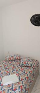 a bed with a colorful comforter with a laptop on it at Suítes com piscina Praia do Forte Tomas in Praia do Forte