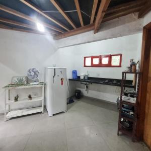 a kitchen with a white refrigerator and a counter at Vila das Acácias in Vale do Capao