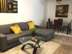 ein Wohnzimmer mit einem Sofa und einem Tisch in der Unterkunft AC Rooms, Smart TV, Centric & 20 mins from Airport in Loiza