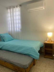 1 dormitorio con 1 cama y mesita de noche con lámpara en AC Rooms, Smart TV, Centric & 20 mins from Airport, en Loiza