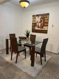 a dining room with a glass table and chairs at AC Rooms, Smart TV, Centric & 20 mins from Airport in Loiza