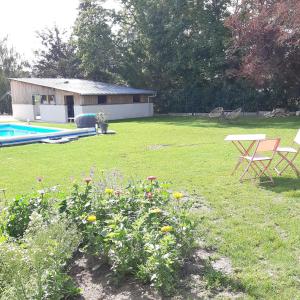 un patio con piscina, mesa de picnic y flores en L'As de Seur, en Seur