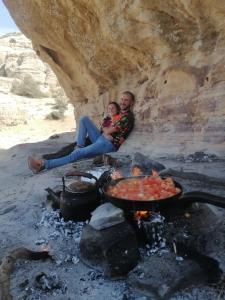 un homme et une femme assis à côté d'un feu dans l'établissement Dana Nabil Ecu Camp House - Main Gate Dana nature reserve, à Dana