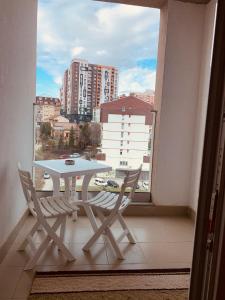 einen weißen Tisch und Stühle auf einem Balkon mit Fenster in der Unterkunft Spacious apartment next to Royall Mall on B Street in Pristina