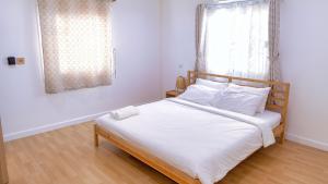 華欣的住宿－Baan Casita With Private Seaside Cottage，一间卧室配有一张带白色床单的床和一扇窗户。
