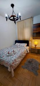 1 dormitorio con cama y lámpara de araña en Lux Apartment Rose 2 60m2, en Kragujevac