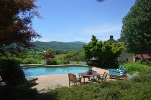 a swimming pool with chairs and a table and a tablektop at Fairhill Farm Country Vacation Rentals in Stanardsville +29 photos