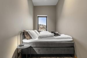 Bett in einem Zimmer mit Fenster in der Unterkunft Toppleilighet på bryggen i Sogndal med fantastisk utsikt in Sogndal