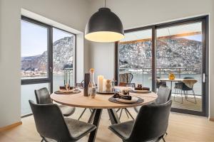 ein Esszimmer mit Tisch und Stühlen und Fenstern in der Unterkunft Toppleilighet på bryggen i Sogndal med fantastisk utsikt in Sogndal