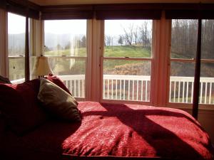 a bedroom with a red bed and a large window at Fairhill Farm Country Vacation Rentals in Stanardsville