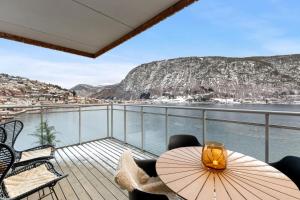 een balkon met een tafel en stoelen en uitzicht op het water bij Toppleilighet på bryggen i Sogndal med fantastisk utsikt in Sogndal